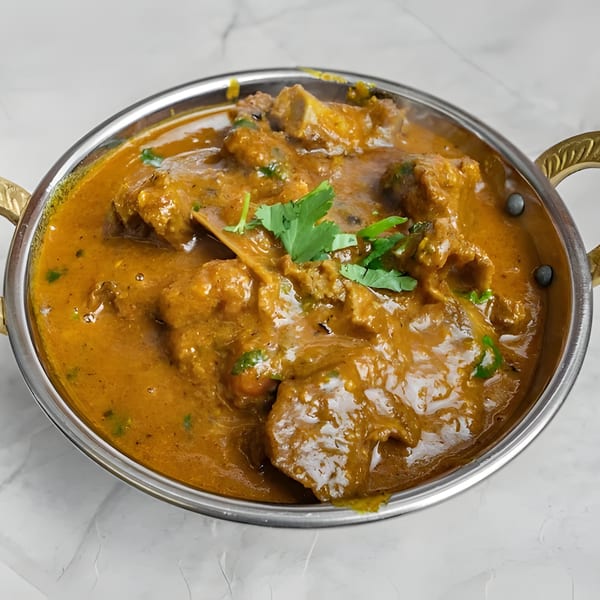 Royal India Palace's Indian curry with meat and cilantro in a metal bowl.