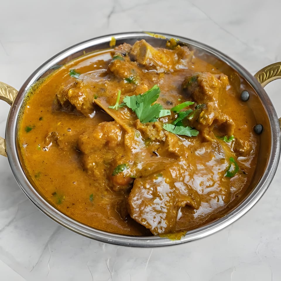 Royal Indian Palace's Indian curry dish, garnished with fresh cilantro, in a metal serving bowl.