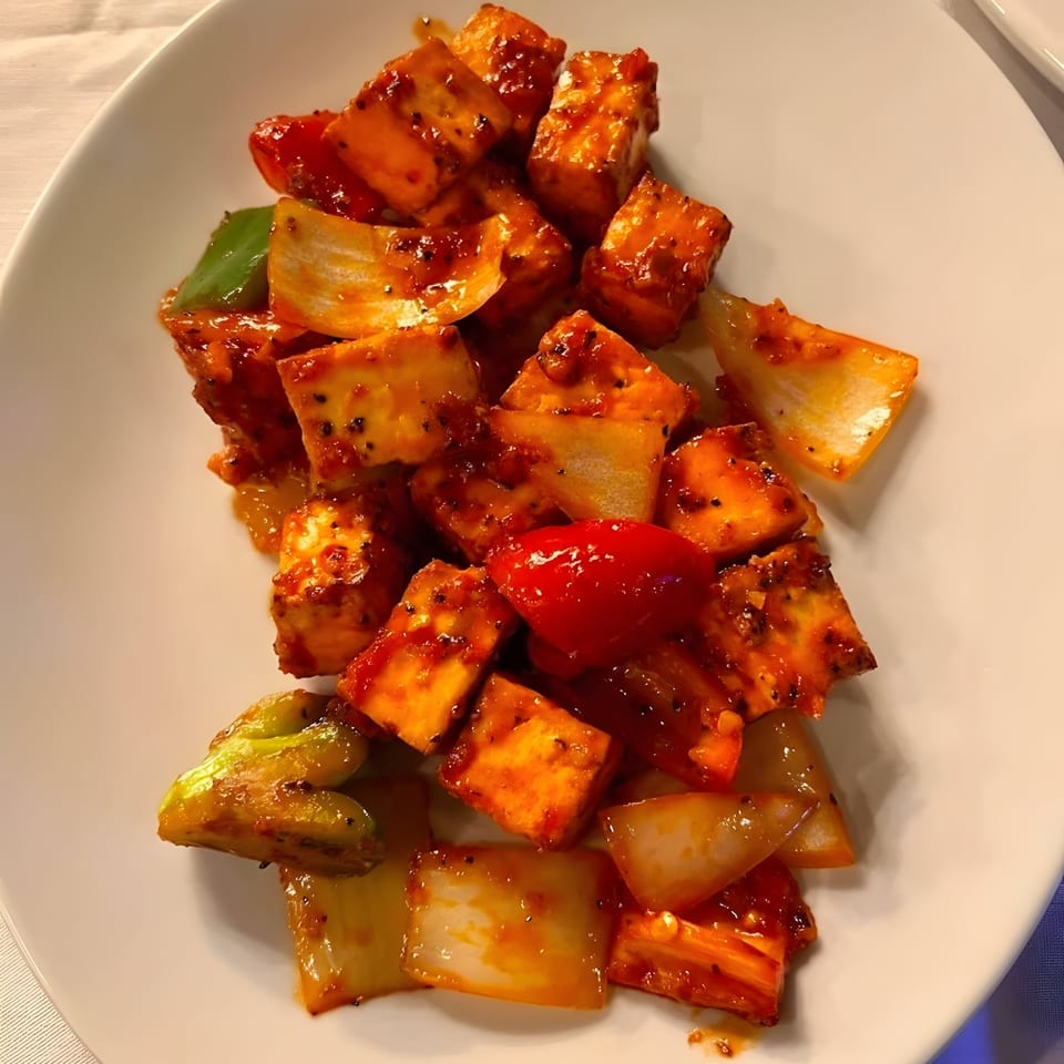 Royal India Palace's chili paneer, featuring paneer cubes, bell peppers, and onions in a spicy sauce.